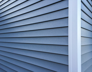 Close-up view of blue vinyl siding on the corner of a building, showcasing clean, straight lines and the smooth texture of the siding panels.